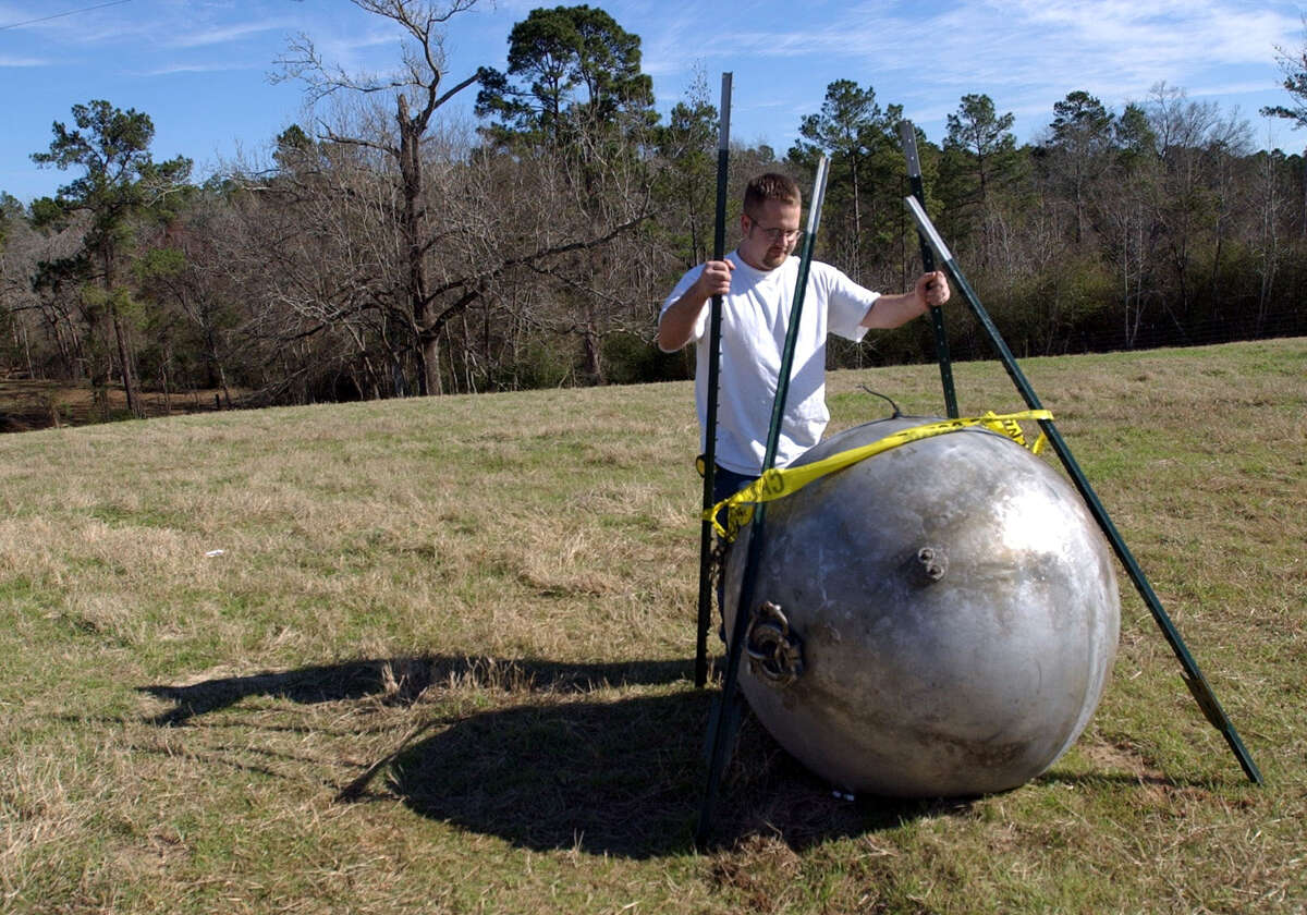(2/4/03) Andy Hawthorne stands next to a fuel cell from the downed Columbia spce shuttle Tuesday morning, which exploded over eastern Texas Saturday and crash-landed near Nacogdoches. 