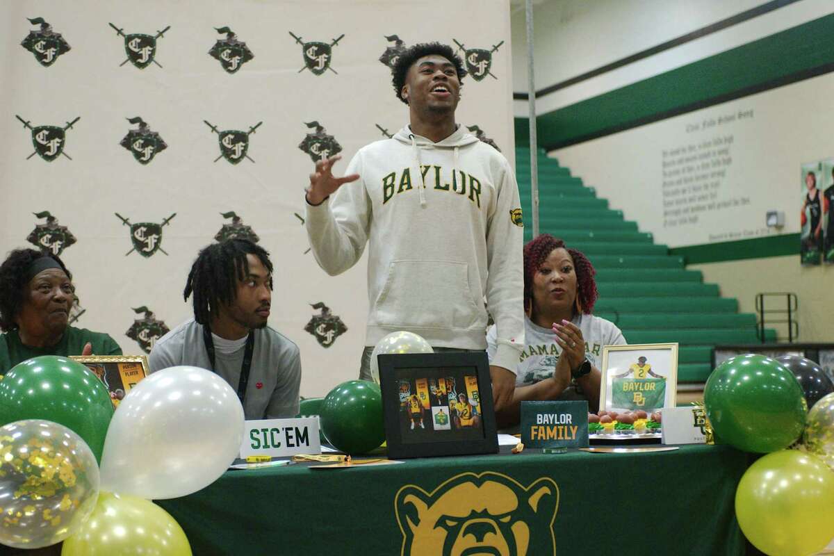Surrounded by his grandmother, Wanda Bennett, his brother, Christian Finley, and his mother, Katrina Howard, Clear Falls graduating senior Corey Kelly gives the Baylor Bear claw as he announces his commitment to play football for Baylor University during signing day Wednesday, Feb. 1, 2023.