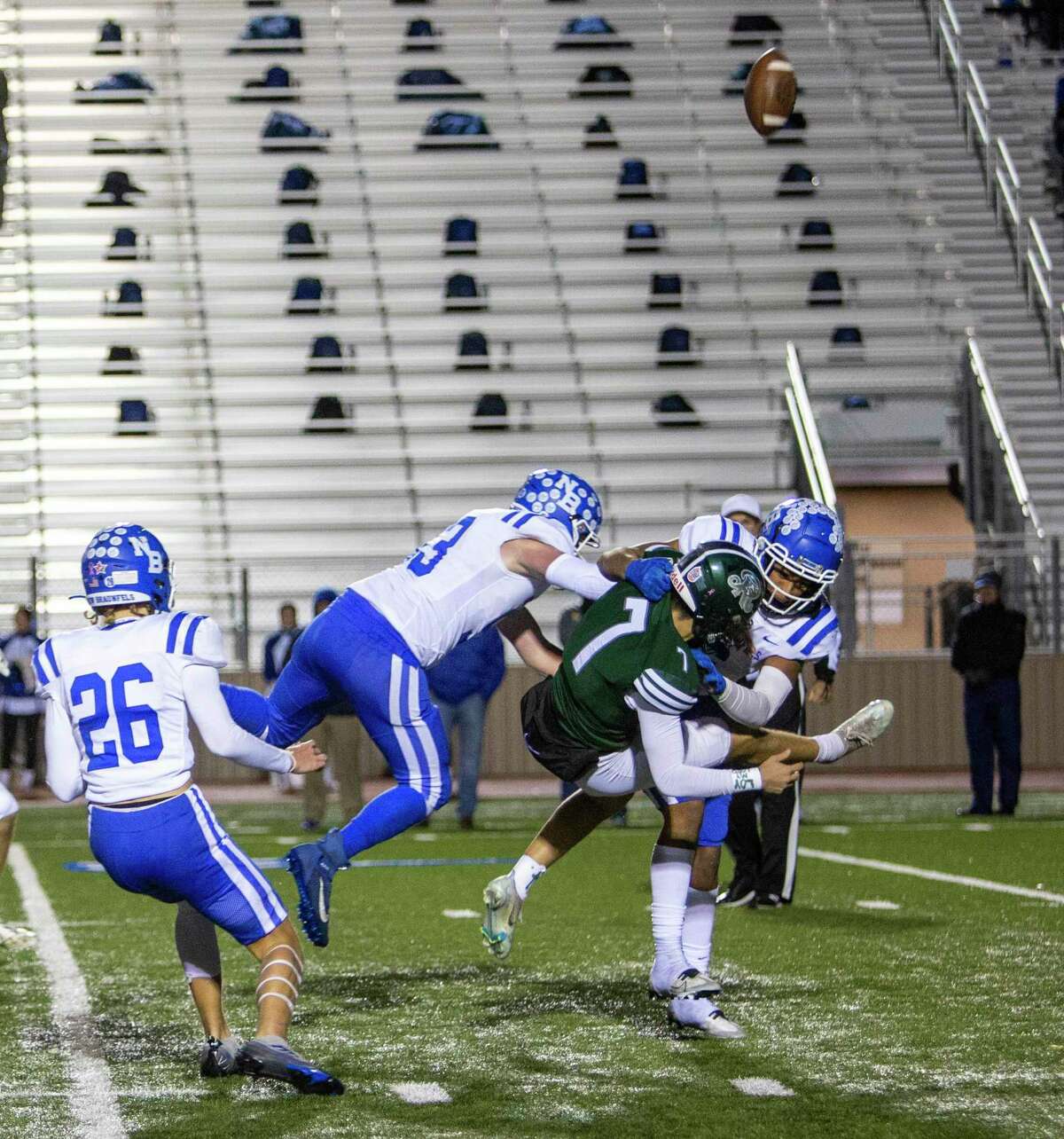 The football flies into the air as Reagan punter Matt Velasco, who signed with Texas State, is tackled Friday night, Nov. 11, 2022 at Comalander Stadium by New Braunfels’ James Archer, left, and Kaden Baerwald after a bad snap caused Velasco to drop the ball. New Braunfels’ Landon Jones is also seen at far left.