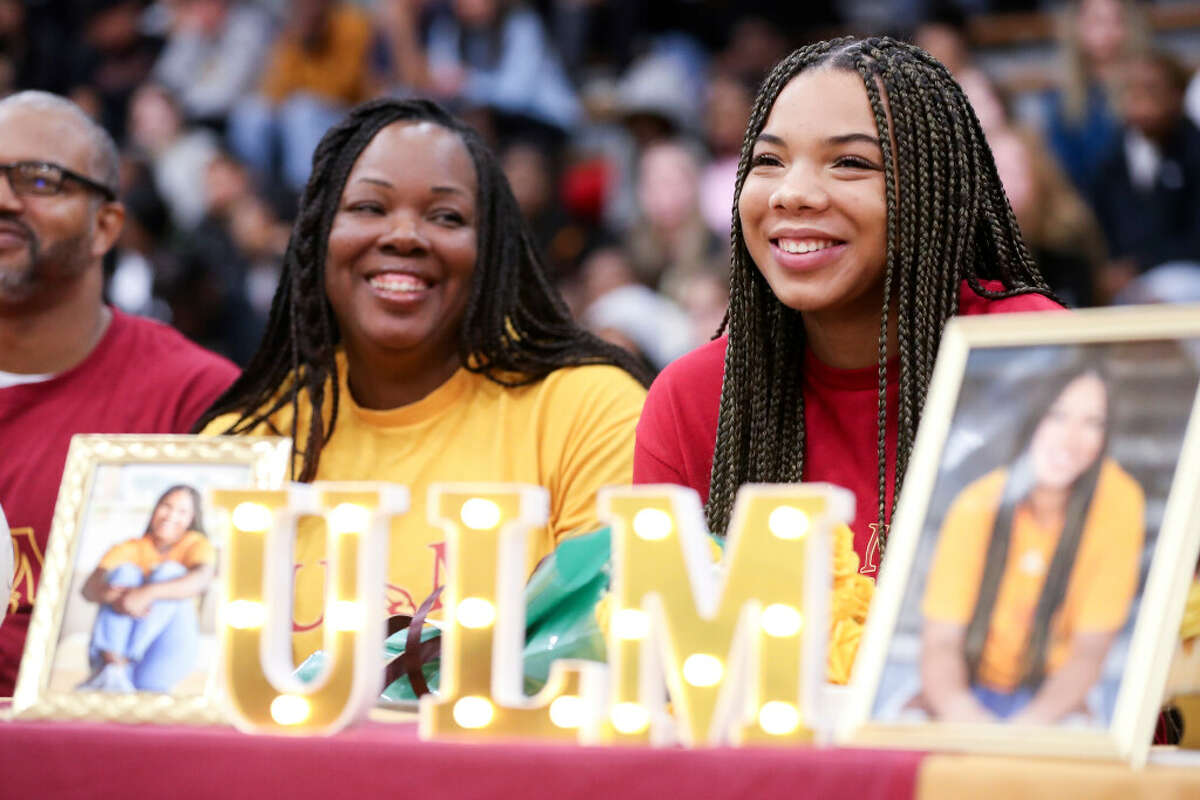 Ariana Brown, right, smiles while her mother and volleyball coach Charvette Brown looks on as football coach Cedric Hardeman tells a story about Ariana’s impact on the program during a ceremony on National Singing Day at Conroe High School, Wednesday, Feb. 1, 2023, in Conroe. Brown, who signed to play volleyball with the University of Louisiana Monroe, joined 10 other Conroe athletes who signed to play sports at the college level.