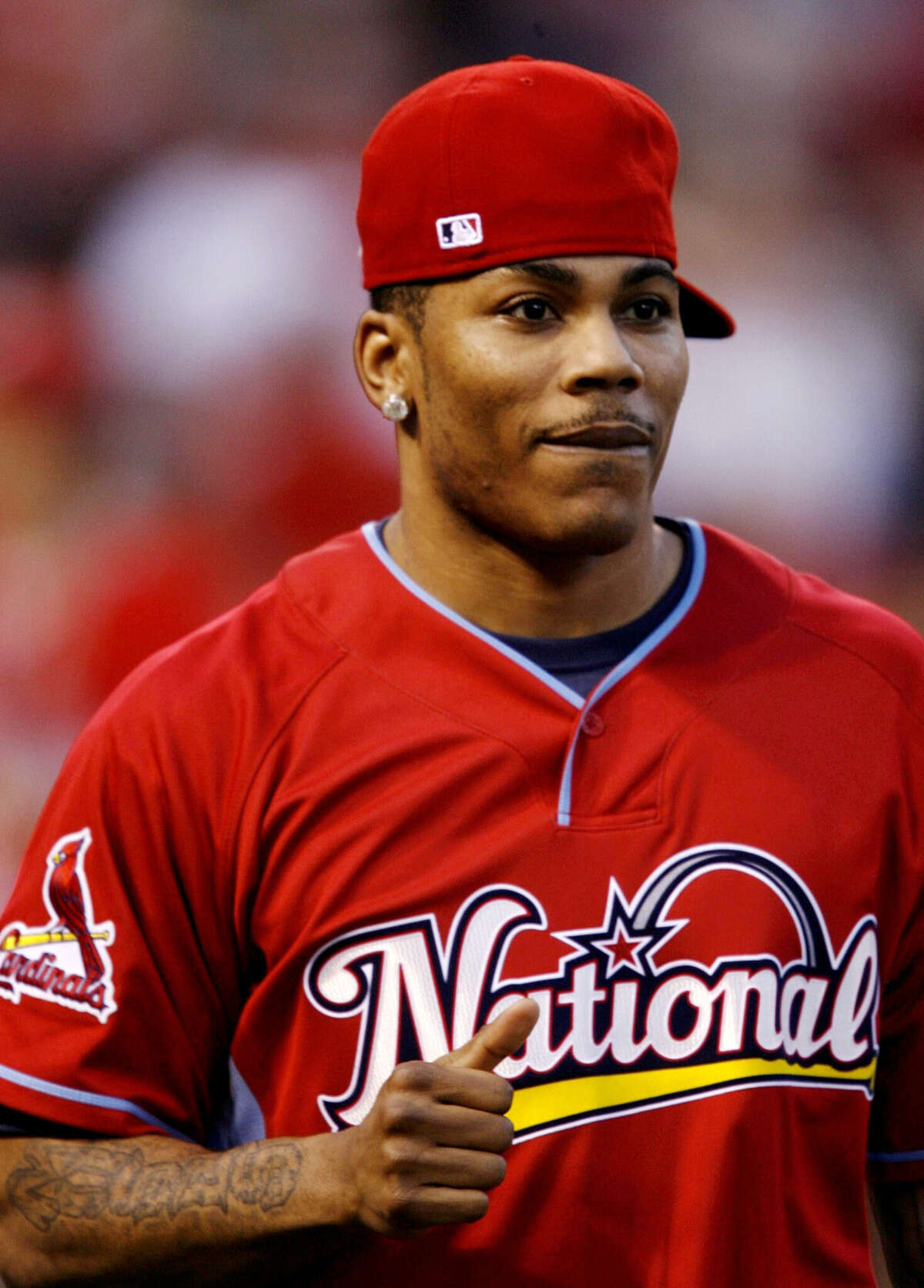 Nelly is dressed in a St. Louis Cardinals baseball cap and a National League baseball jersey. 