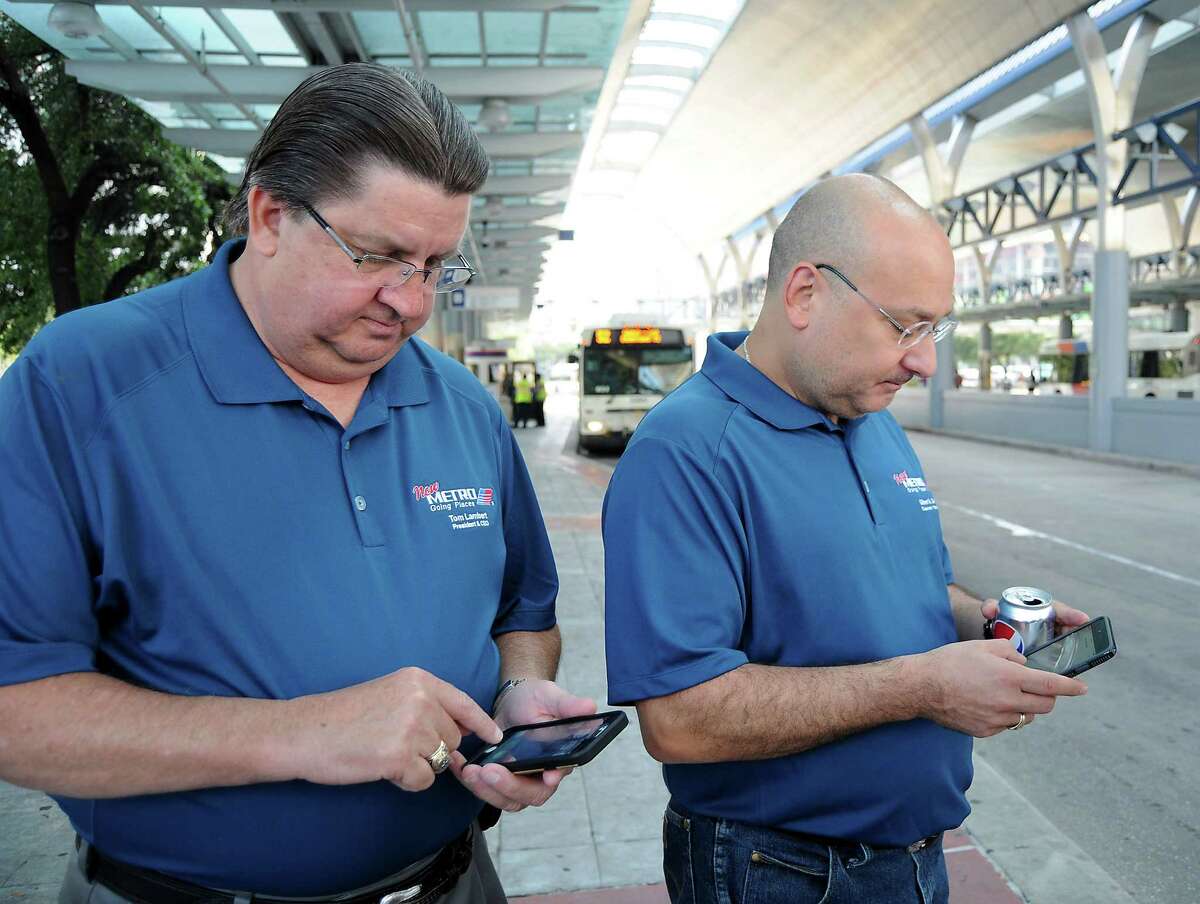 Metro CEO Tom Lambert and Metro chairman Gilbert Garcia use the new app to check arrival times for buses at the Downtown Transit Center Sunday August 16, 2015. The group was celebrating the rollout of the new Metro network.(Dave Rossman photo)