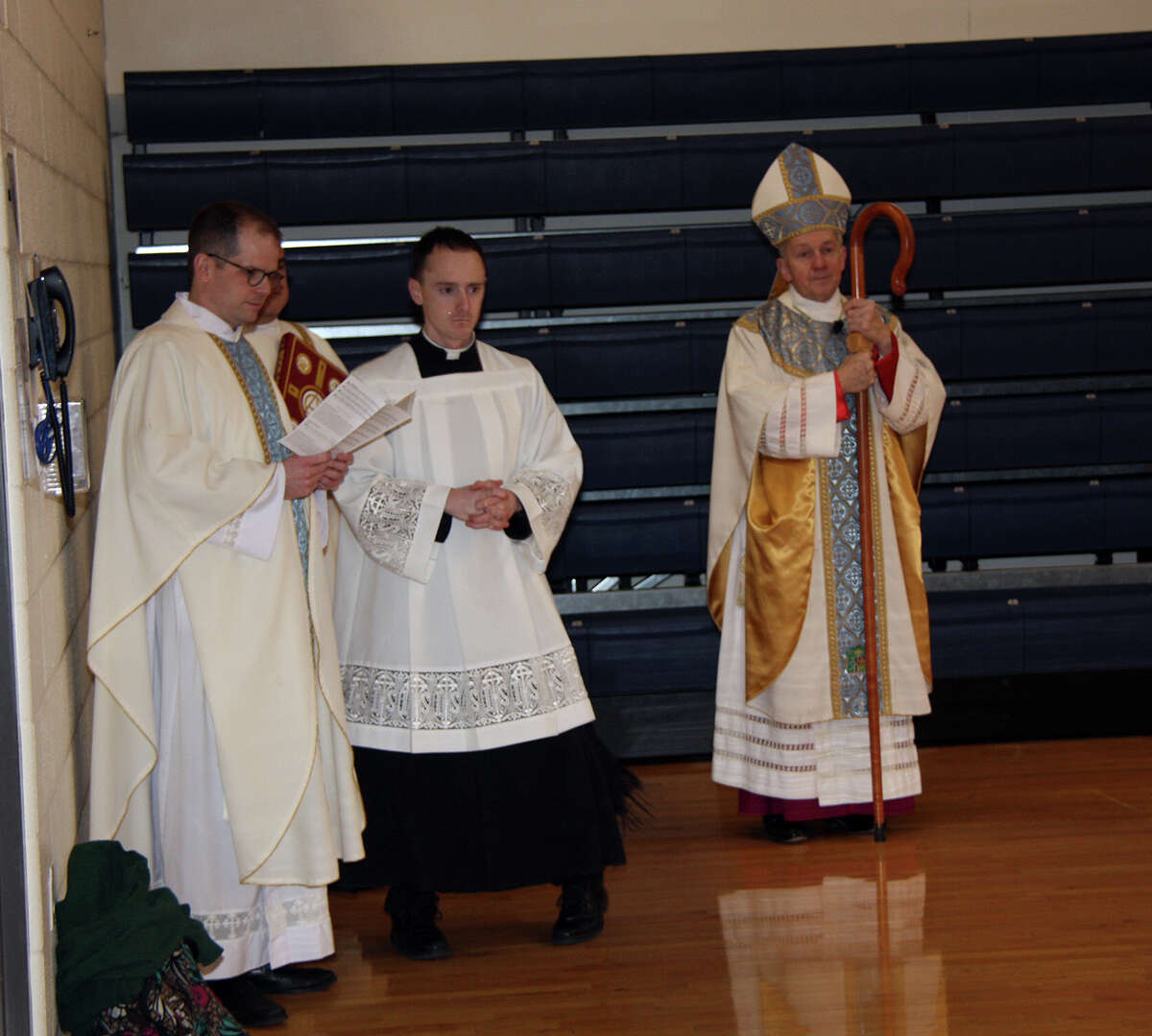 Bishop Thomas Paprocki, right, along with Very Rev. Jeffrey Goeckner, left, and Associate Chaplin Michael Trummer wait in the school gym Thursday. 