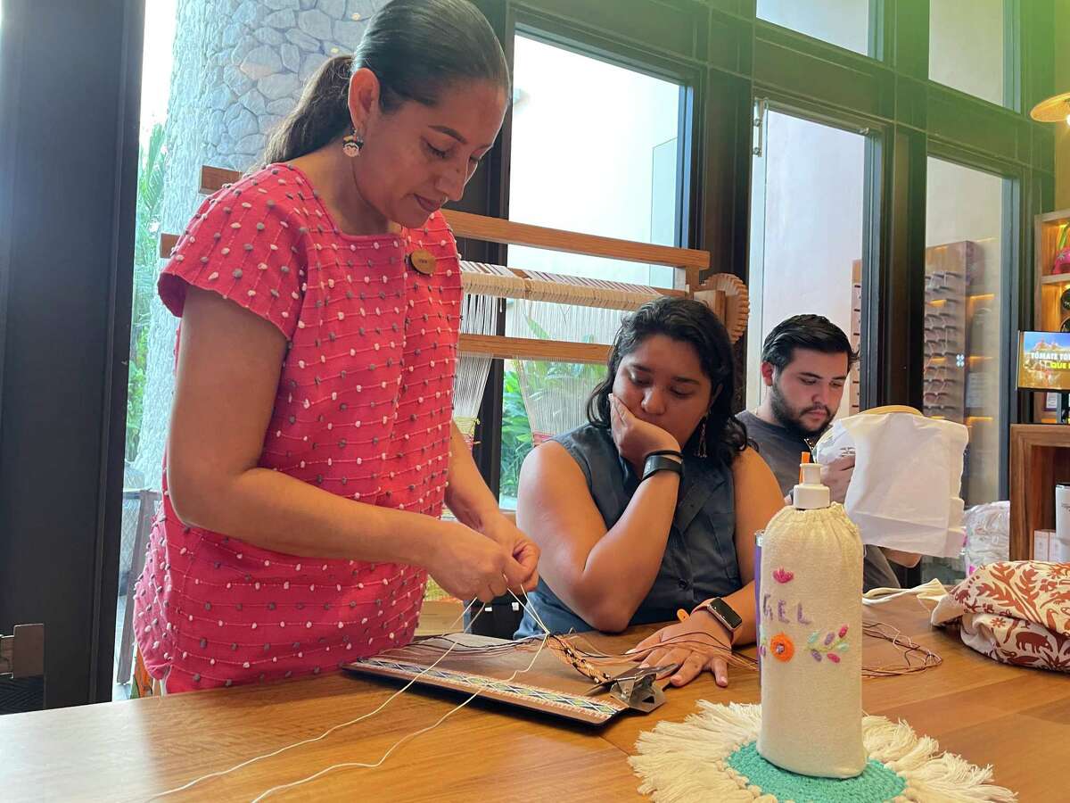 Guests at the all-inclusive Hotel Xcaret Arte can attend free Mexican art and dance workshops. In the textile shop, a staff member teaches guests how to weave and cross-stitch, both traditional Mexican crafts.