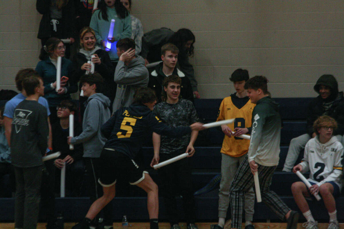 Members of the Manistee student section get into a friendly sword fight with their glowsticks before a game against Whitehall on Feb. 2, 2023 at Manistee High School. 
