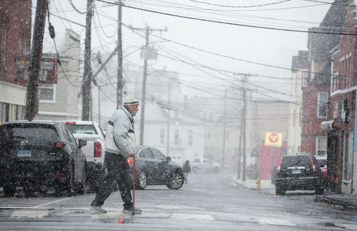 A pedestrian crosses Keeler Street as a wet snow falls in the Danbury area on Wednesday afternoon. January 25, 2023, Danbury, Conn.
