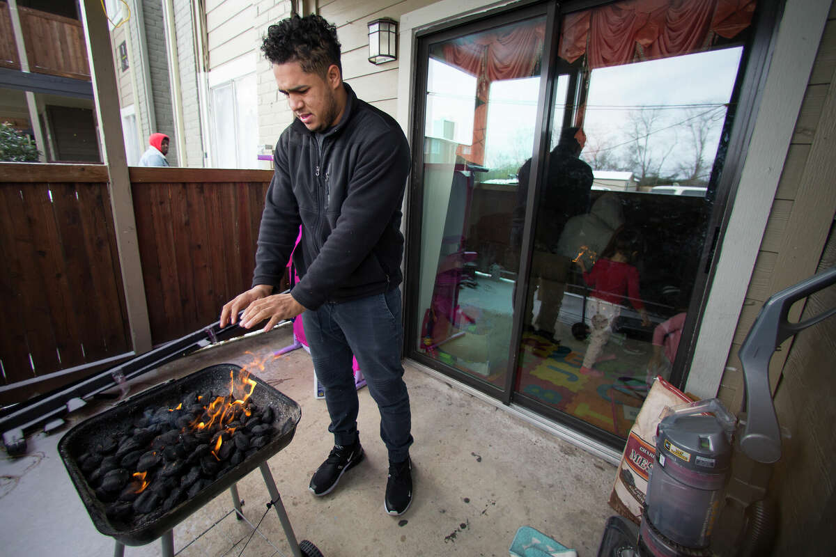 Kevin Morazan warms his hands after lightning his charcoal grill to cook after losing power in the Greenspoint area due to rolling blackouts following an overnight snowfall Monday, Feb. 15, 2021 in Houston. A judge ruled that natural gas companies Anadarko, Apache, Atmos, Comstock, El Paso, Energy Transfer, Kinder Morgan and XTO will not have to stand trial for any damage or deaths caused by power outages during the four days in which Texas was hit with record cold temperatures and sleet and snow.