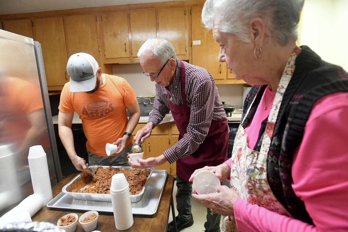From left, volunteers Jeremy Page, Duane Baker and Peggy Whitehead portion out the pulled pork servings during a bar-b-que fundraiser for the Buna Public Library. The annual event is among the library's main sources of funding, in addition to other fundraising events and grants. Photo made Thursday, January 19, 2023 Kim Brent/Beaumont Enterprise