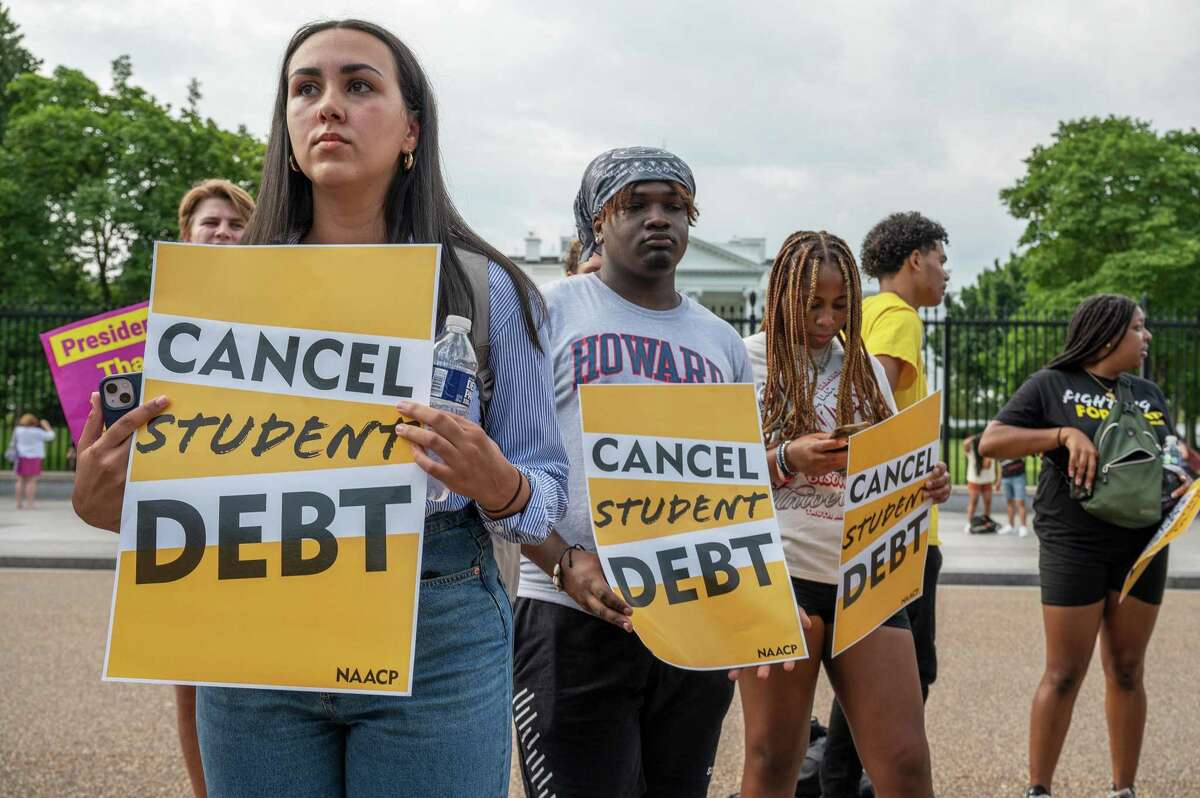 Sabrina Calazans, director of borrower outreach at Student Debt Crisis Center, and Howard University students Aiden Thompson and Sydney Stokes rally with other student loan debt activists outside the White House on Aug. 25, 2022.