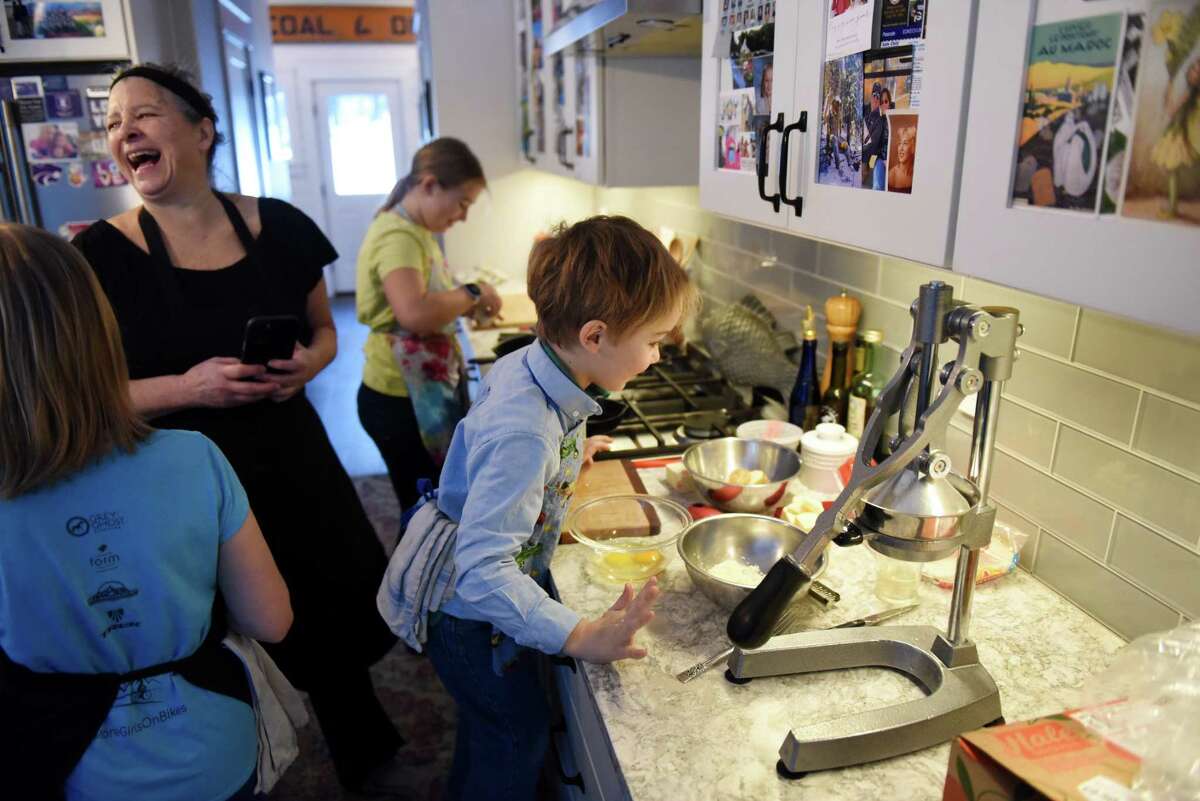 Kim Klopstock, left, lets out a laugh as she coaches grandchildren; Johnsie Parker Hedgpeth, 8, left, Leila Hedgpeth, 10, center, and Teddy, 5, right, on how to cook their breakfast on Friday, Feb. 3, 2023, at the Hedgpeth home in Greenfield Center, N.Y.