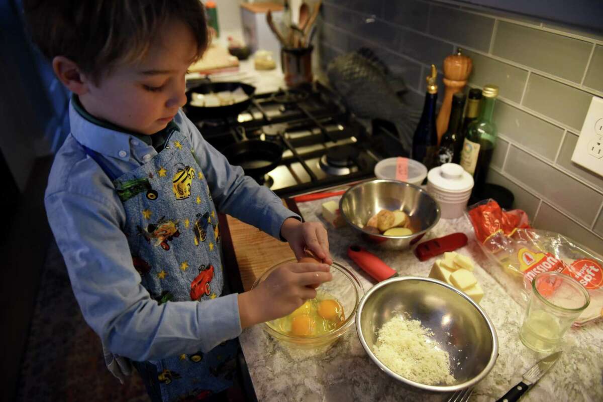 Teddy Hedgpeth, 5, right, breaks eggs for a breakfast meal as he and his siblings cook under the guidance of their grandmother, Kim Klopstock, on Friday, Feb. 3, 2023, at the Hedgpeth home in Greenfield Center, N.Y.