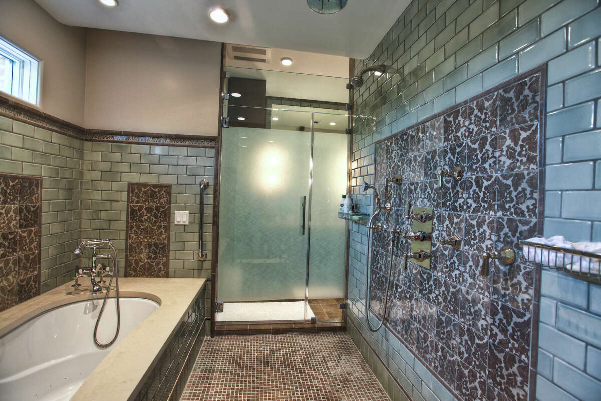 The primary bathroom has a walk-through shower that leads to separate vanities and toilet rooms.