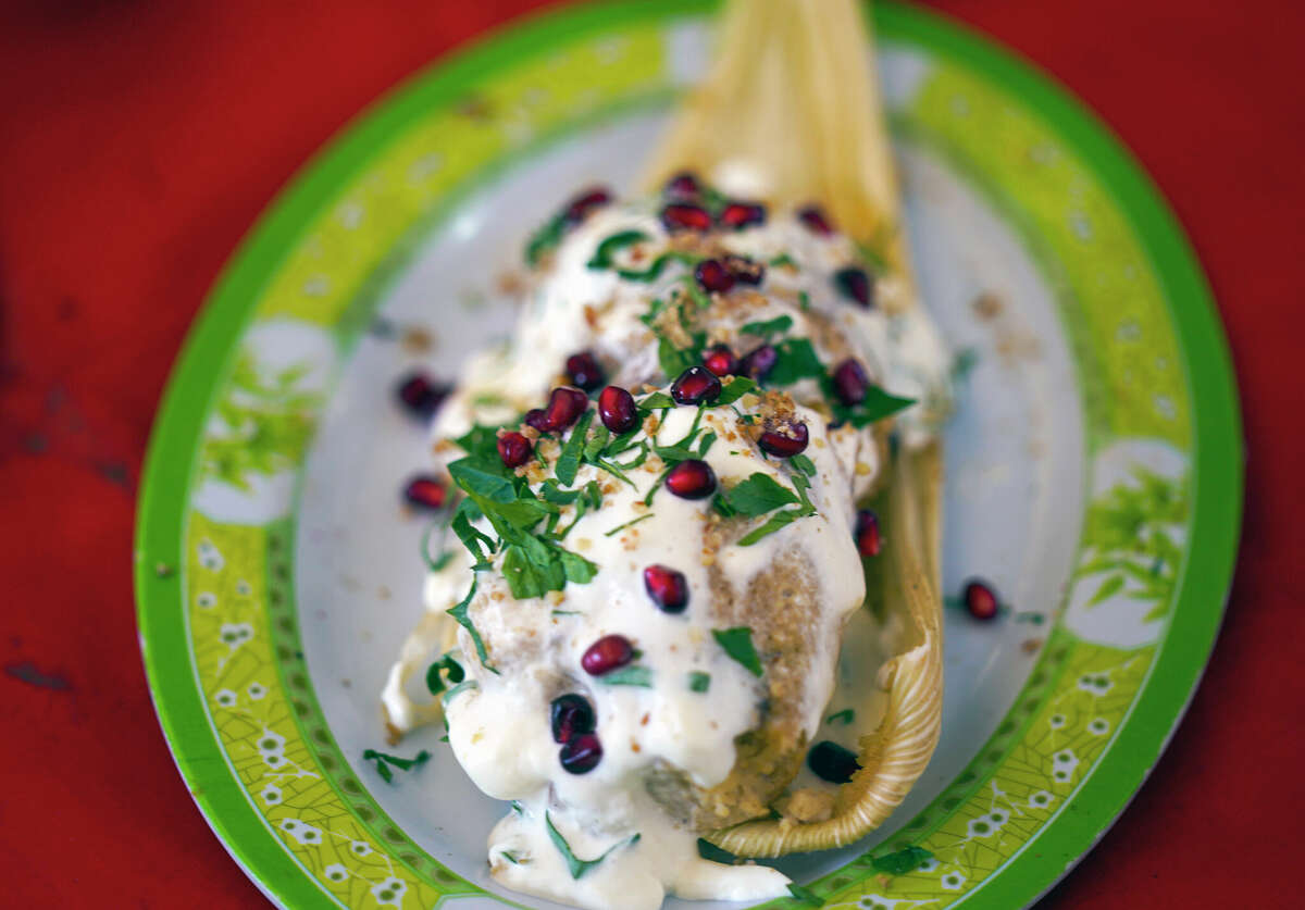 A Chiles en Nogada style tamal is displayed in late January during the tamales fair in the Ixtapalapa neighborhood of Mexico City. Chiles en nogada is a Mexican dish of poblano chiles stuffed with picadillo topped with a walnut-based cream sauce called nogada, pomegranate seeds and parsley, and it is typically served at room temperature. It is widely considered a national dish of Mexico.