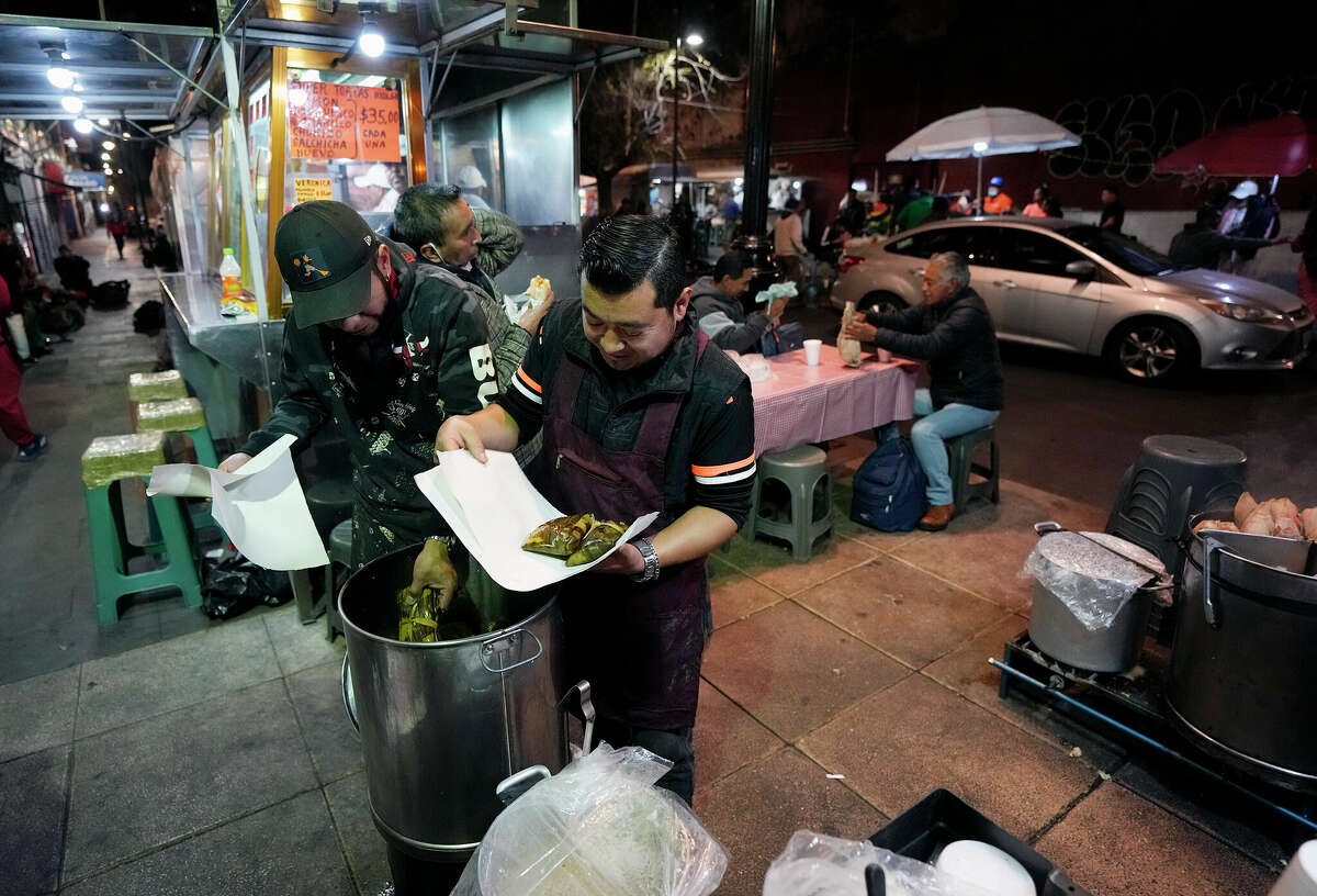 Streets vendors sell Oaxaca style tamales at a corner stand in down town Mexico City. Oaxaca style tamales consist of a tamal stuffed with shredded meat and mole sauce, and then wrapped and cooked with banana leaves.