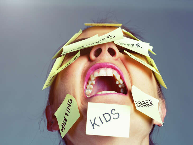 A furious woman covered with Post-it reminders of things to do has had enough, puts her head back and shrieks!