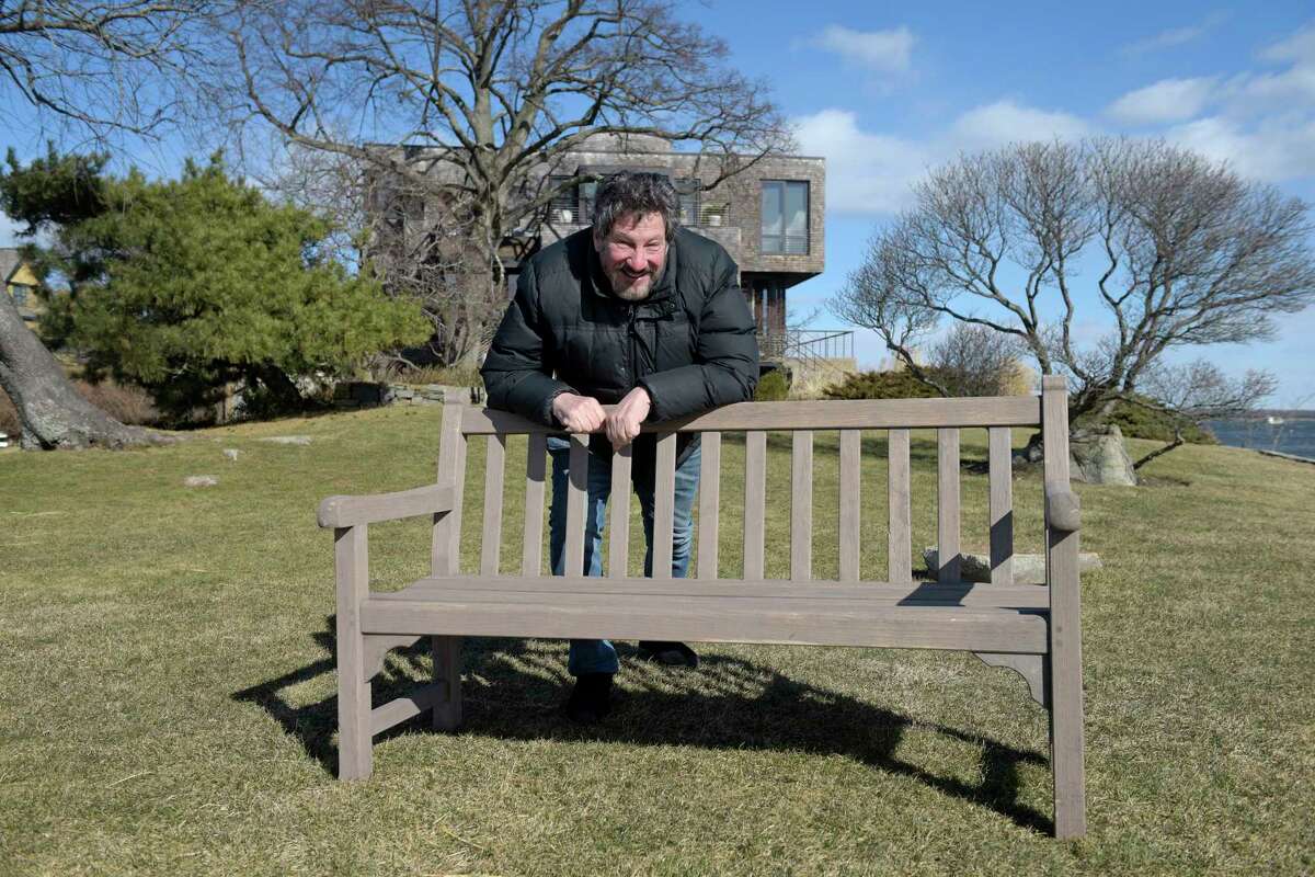 Dean Hacohen with a bench dedicated to his parents at the lookout area at the tip of Rocky Point on Bell Island. That bench had just returned on Wednesday from a trip to Long Island, 17 nautical miles away, that started in November. The bench disappeared, it was presumed to have washed away in a storm, only to be found by a couple on a Long Island beach. Friday, February, 3, 2023, Norwalk, Conn.