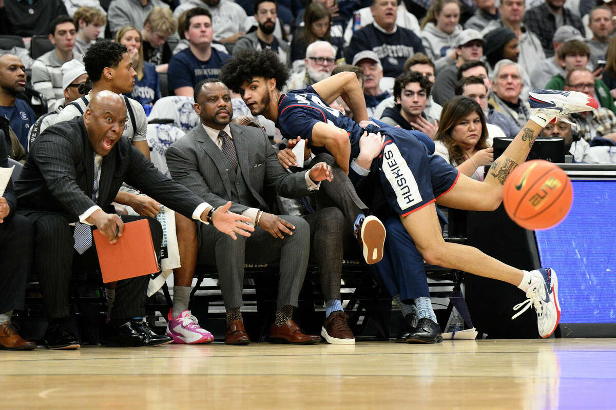 Connecticut guard Andre Jackson Jr. (44) crashes into the Georgetown bench after he chased the ball during the first half of an NCAA college basketball game, Saturday, Feb. 4, 2023, in Washington. (AP Photo/Nick Wass)
