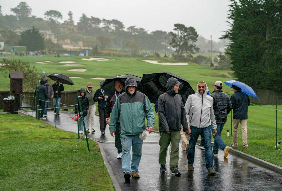 Spectators walk past the 4th hole at the Pebble Beach Golf Links after wind and bad weather caused a delay during the AT&T Pebble Beach Pro-Am on Saturday, Feb. 4, 2023 in Pebble Beach, Calif.