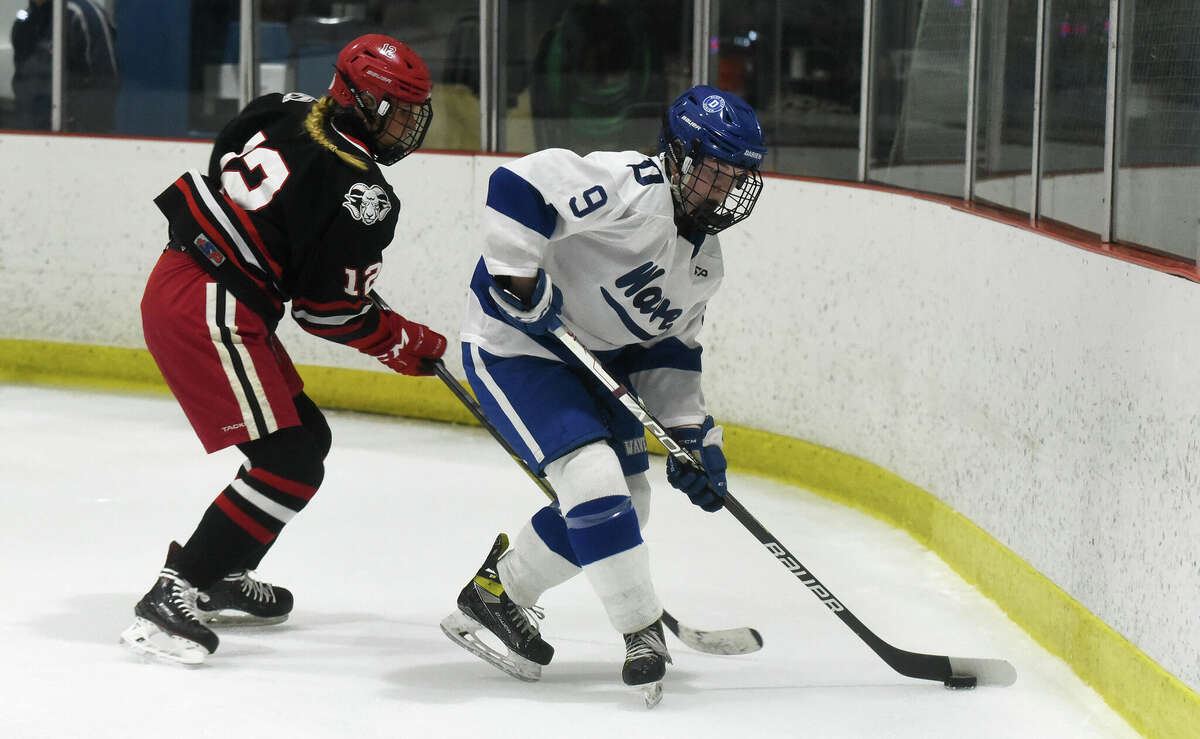 Darien's Natalie Beach (9) controls the puck while New Canaan's Amanda Benson (12) defends during a girls ice hockey game at the Darien Ice House on Saturday, Feb. 4, 2023.