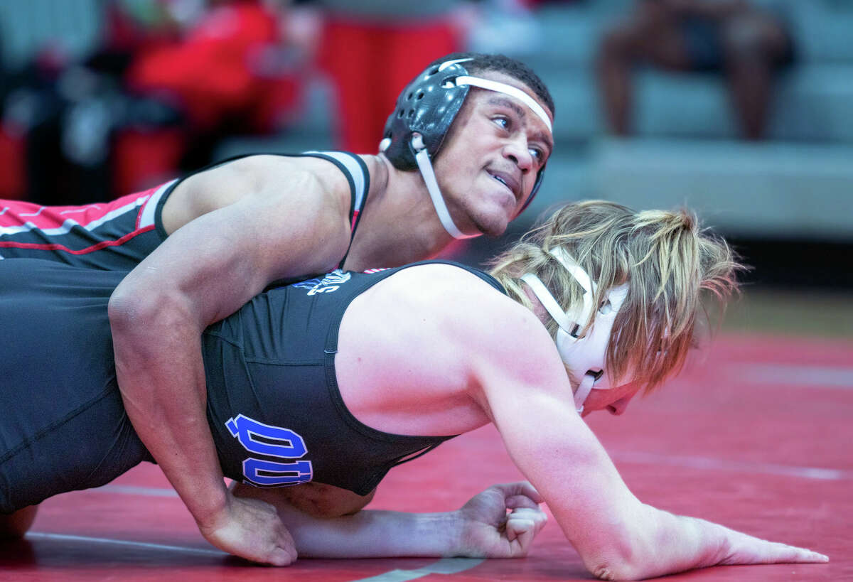 Alton's Antoine Phillips, top, looks at AHS coach Eric Roberson as he wrestles with Quincy's Gunnar Derhake in a semifinal bout Saturday at the IHSA Class 3A Regional at Alton High School. Phillips won 8-3 and went on to finish second in the weight class.