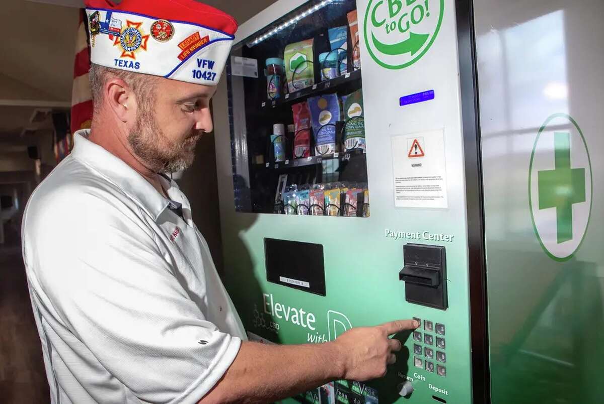 Dave Walden, wearing a Veterans of Foreign Wars cap, demonstrates how the CBD vending machine works by purchasing a product in Leander on Nov. 1.