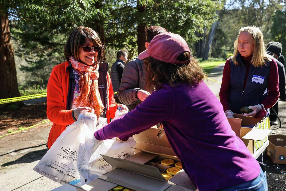 Eunice Vergara (left) picks up food for her mother-in-law from the SF-Marin Food Bank’s pop-up pantry in the Outer Richmond. The food bank is preparing to see more demand as pandemic-era supplements to food assistance programs come to a close.