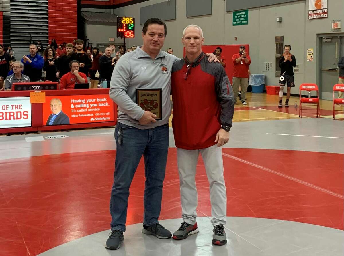 Edwardsville coach Jon Wagner was presented with a plaque commemorating his 27-year career with the Tigers by Alton coach Eric Roberson at the Class 3A Alton Regional on Saturday in Godfrey. Wagner will retire as boys wrestling coach at the end of the season.