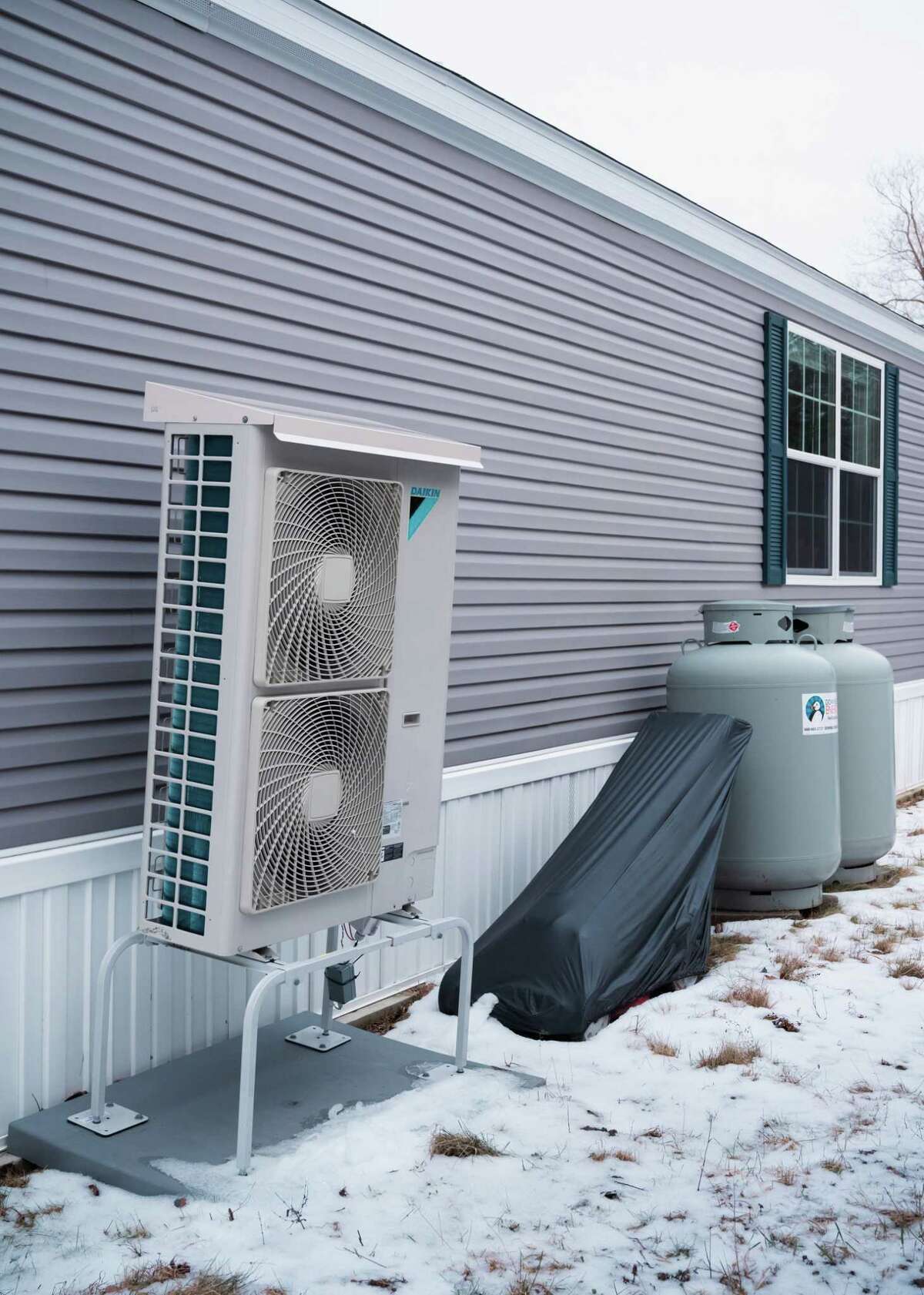 A new heat pump and propane tanks sit on the outside of Casagranda's home. The devices are growing in popularity in New England, in part because of improved energy efficiency and new tax incentives.