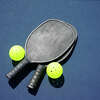 Two pickleball paddles and two pickleballs on court