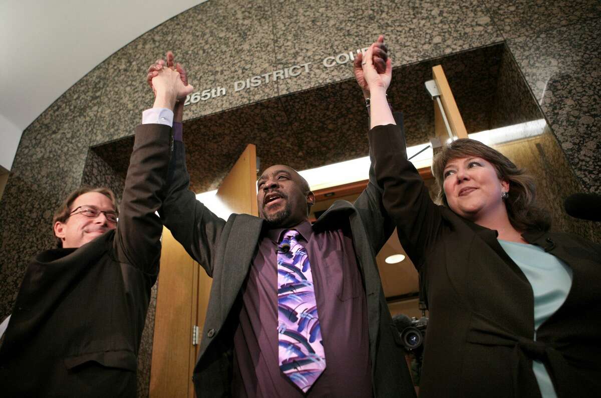 James Lee Woodard, center, raises his arms in victory as he leaves a Dallas courtroom with Innocence Project Texas director Jeff Blackburn and public defender Michelle Moore on April 29, 2008. Woodard was exonerated for the 1981 strangulation and rape of his 21-year-old girlfriend, Beverly Ann Jones.