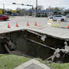 Traffic passes by a hole where a water main break, resulting in a sink hole at the northeast corner of the Tidwell and Antoine intersection is being repaired Tuesday, Feb. 7, 2023 in Houston, TX. The break caused water outages to some 100 homes in adjacent neighborhoods.