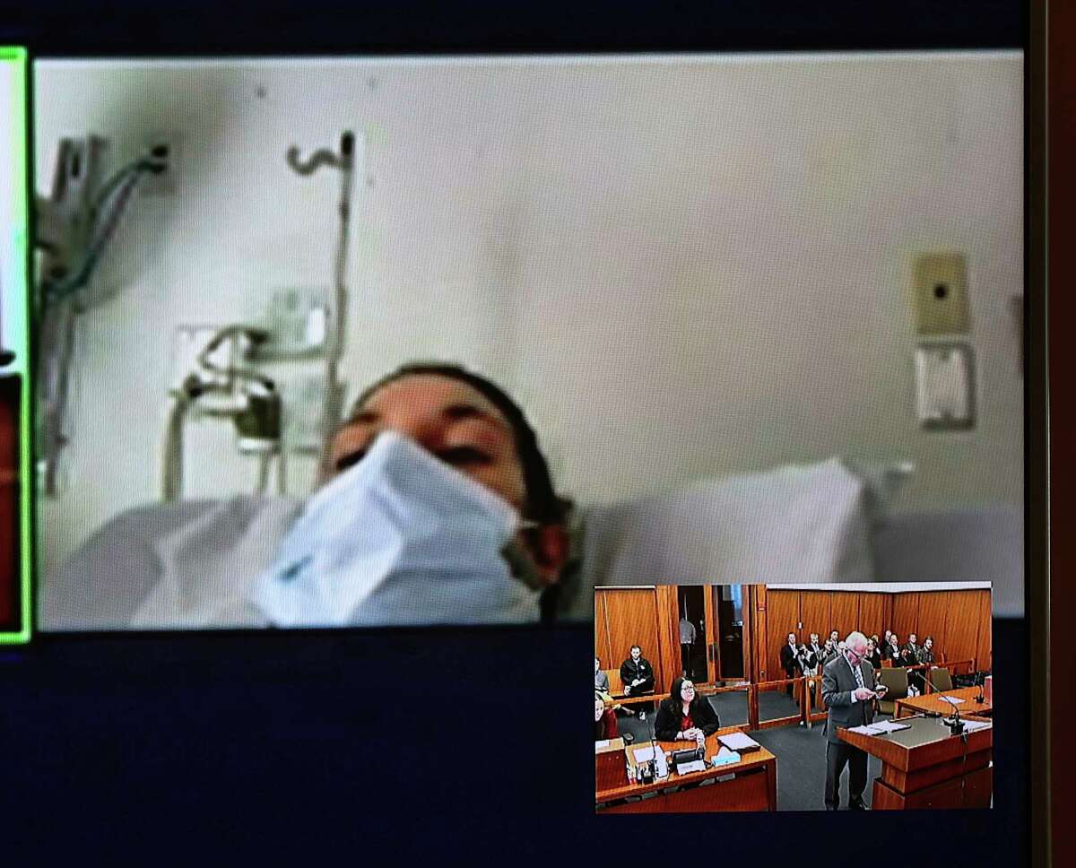 In this video screen image, Lindsay Clancy with a surgical mask over her face in a hospital appears during her arraignment on charges regarding her three children's deaths at Plymouth District Court Tuesday, Feb. 7, 2023, in Plymouth, Mass. With District Court Judge John Canavan as the presiding judge the defendant participated remotely through video conference. Not guilty pleas were entered on behalf of 32-year-old Clancy to charges including murder, strangulation and assault and battery at her arraignment. 