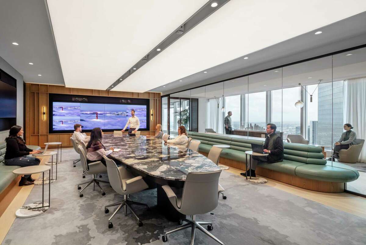 The main board room at Hines has a stone-topped table with built-in, pop-up microphones, numerous screens for those who attend virtually and extra seating in the form of curvy leather banquettes.