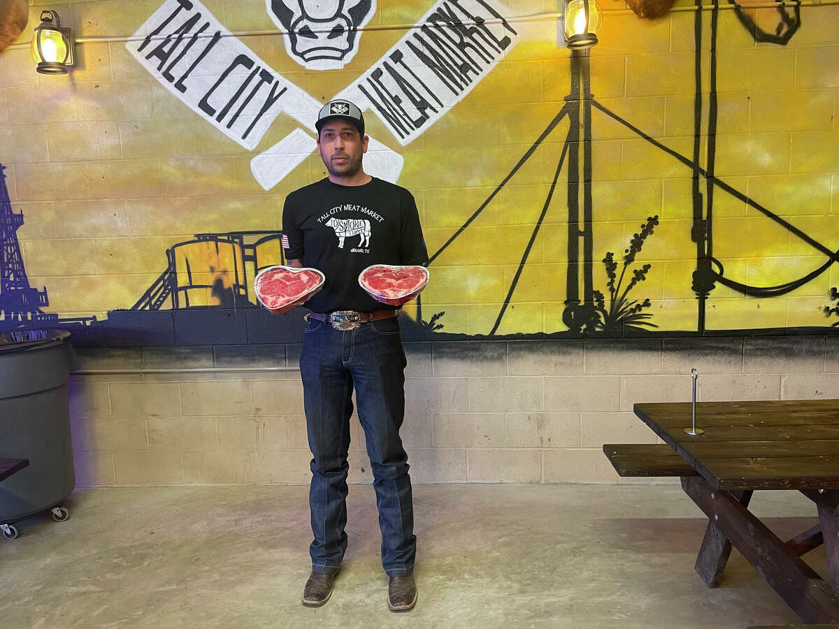 Tall City Meat Market owner Michael Loya holds up a pair of Valentine's Day steaks. 