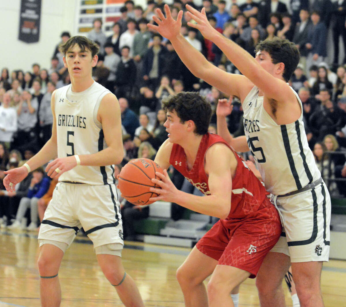 Tommy Scholl of Fairfield Prep looks for a teammate while being guarded by Kevin Goldberg of Guilford. Justin hess (5) of Guilford looks on.