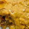 A zoomed-in photograph of a slice of crawfish-boudin king cake topped with crawfish queso at Crescent City Connection, a bakery in Webster, Texas.