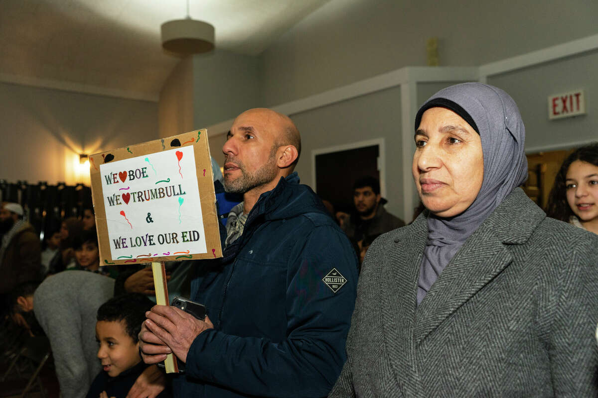 Gamal Mofadal, accompanied by his mother in law Ayda Moustafa, holds a placard supporting Muslim parents' push to have the district recognize Eid as a school holiday at a Feb. 7, 2023 Trumbull Board of Education meeting.
