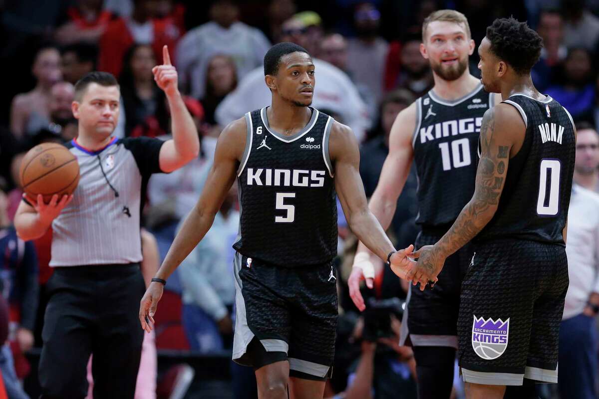 Referee Gediminas Petraitis, left, signals one more free throw as Sacramento Kings guard De'Aaron Fox (5) is congratulated by Malik Monk (0) and Domantas Sabonis (10) after Fox hit the go-ahead free throw in the final second of an NBA basketball game Wednesday, Feb. 8, 2023, in Houston. (AP Photo/Michael Wyke)