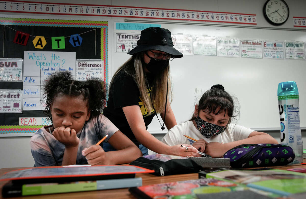Rebecca Flores helps Stephanie Jones, left, and Zoey Garcia learn about decimal points during her math class Tuesday, July 26, 2022, at Aldine ISD's Ermel Elementary School in Houston.