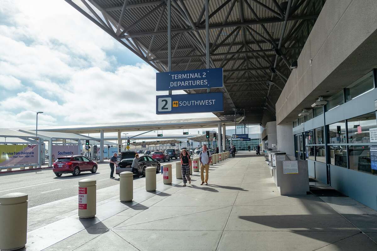 Travelers walk under departures sign for Southwest Airlines at Oakland International Airport in May 2021.