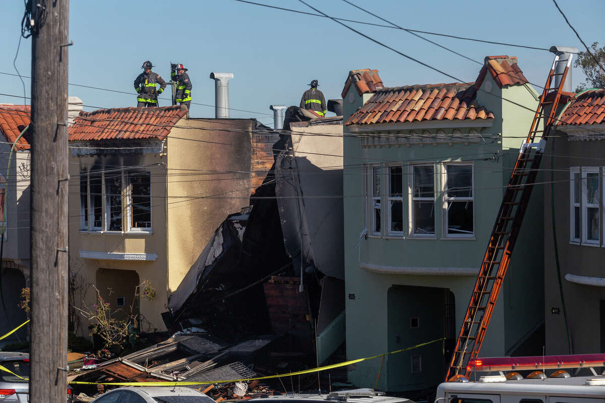 Firefighters stand on an adjoining structure from a home on the 1700 block of 22nd Avenue in the Sunset District that completely collapsed after a fire consumed the structure in San Francisco on Feb. 9, 2023.