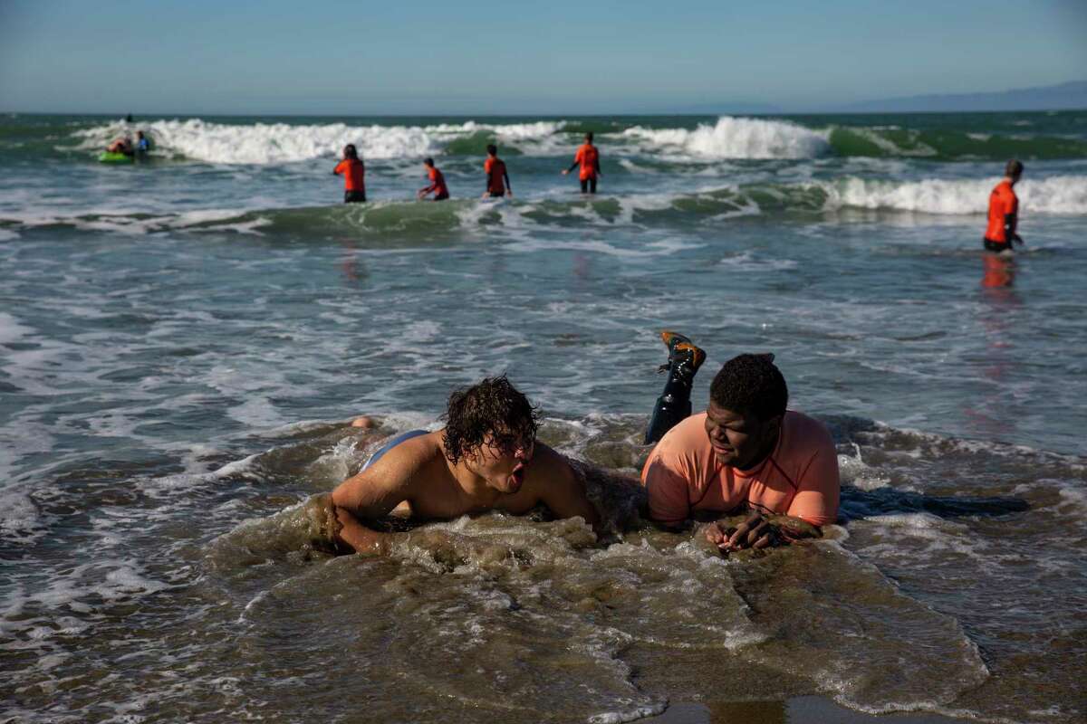 DeMarcus Jackson, left, 17, and Damiane Fisher, right, 16, surf club students from Mission High School in San Francisco, hang out in the water after an afternoon of surfing with City Surf Project at Linda Mar Beach in Pacifica.