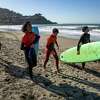 (从左到右)冲浪俱乐部的学生，17岁的Atticus Young, 15岁的Miguel Pimentel, 15岁的Amine Jaawani, 15岁的Axel Tostado，在加利福尼亚州Pacifica的Linda Mar海滩与城市冲浪项目的教练冲浪一天后，走着他们的冲浪板回到汽车上。2023年2月9日星期四。约翰尼·欧文(Johnny Irwin)是城市冲浪项目(City Surf Project)的执行董事，该项目是对帕西菲卡冲浪营地的许可制度提出担忧的非营利冲浪学校之一。