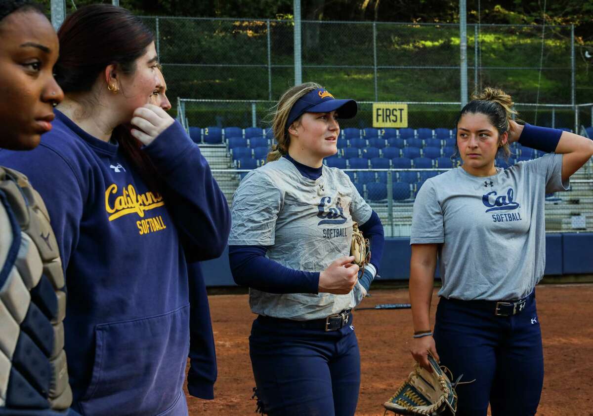 Catcher Makena Smith (center) huddles with her softball teammates during practice at Levine-Fricke Field. Smith also has spent time on the women's soccer team as a goalie.