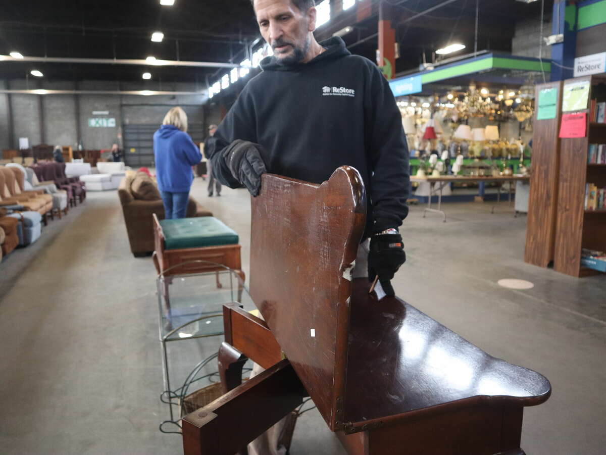 Raymond Garlock demonstrates a folding table originally from the Desmond Hotel Saturday, Feb. 11, 2023 at the Habitat for Humanity ReStore in Albany.