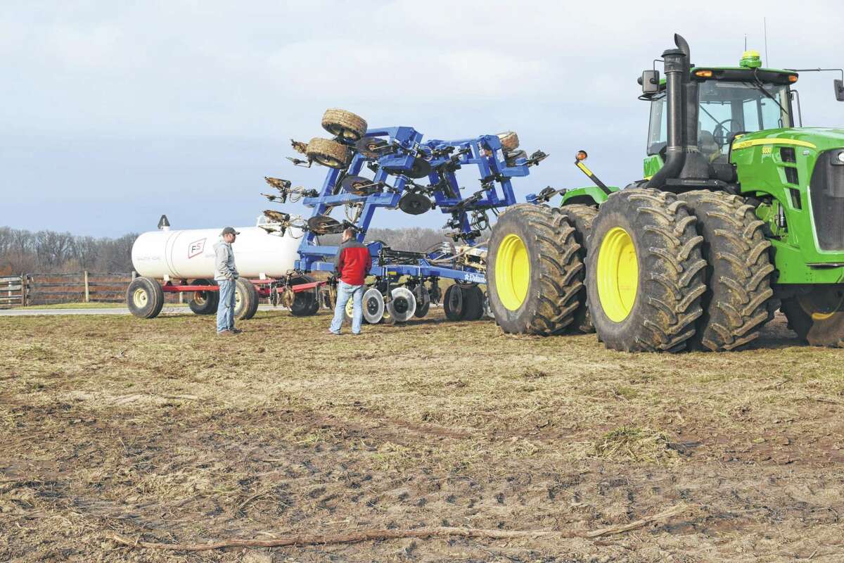 Brothers Kyle Schone (left) and Chad Schone stand near a tractor, anhydrous ammonia applicator and an anhydrous tank Thursday in a field west of Bethel.
