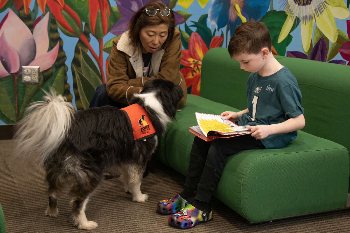 Luke Day, 7, of Wilton reads to Mitsu and her owner Yoko Hirokawa of ROAR as kids read to dogs at the WIlton Library on Saturday, Feb. 11, 2023. 