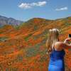 FILE - Renee LeGrand, of Foothill Ranch, Calif., takes a picture among wildflowers in bloom on March 18, 2019, in Lake Elsinore, Calif. A small California city that was overrun by visitors four years ago when heavy winter rains produced a spring 