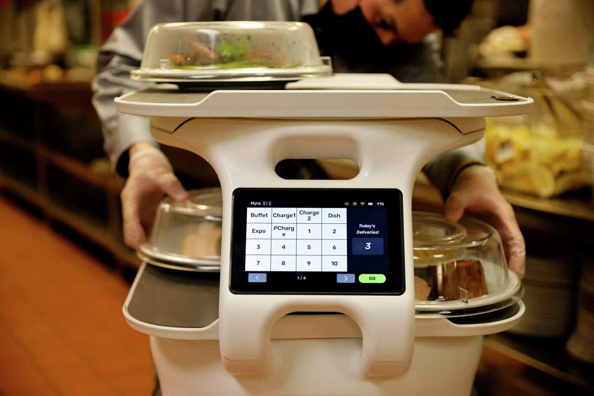 旧金山塔养老院的一个机器人装上了热盘子。机器人将菜肴从厨房运送到餐厅，在那里它与为客人提供食物的服务员相遇。