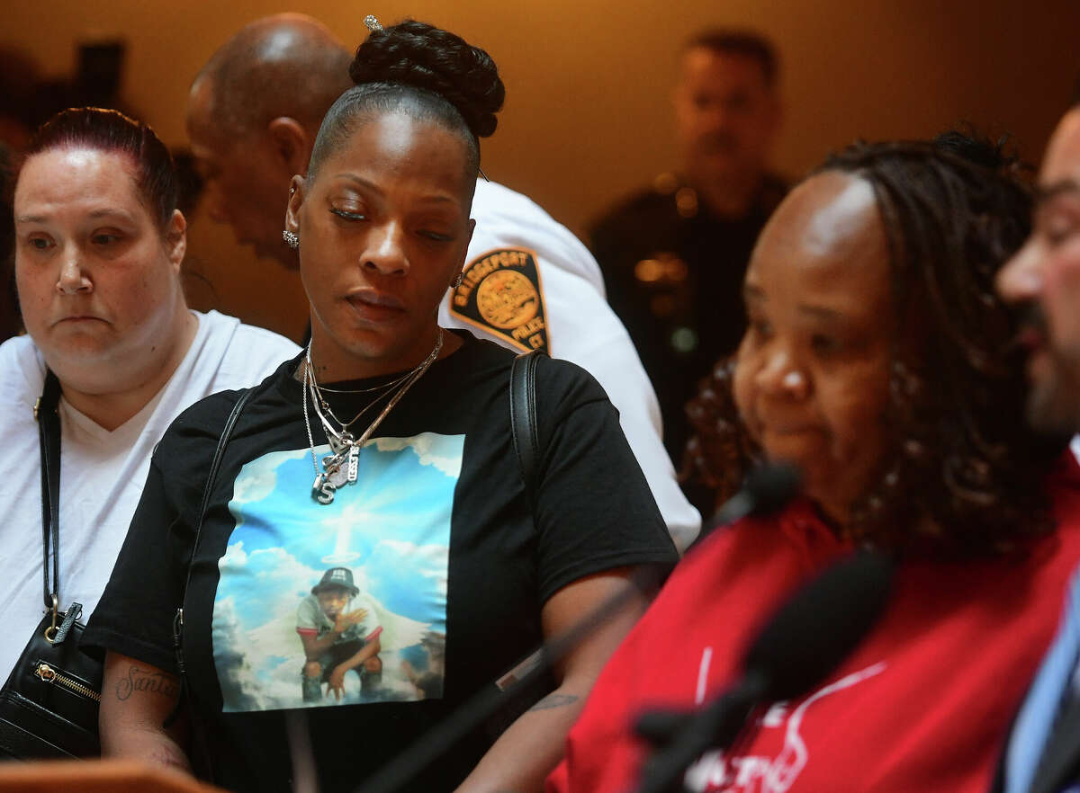 Wearing a shirt memorializing her son, Dominique Jones, a victim four months ago of gun violence, Samantha Jones, of Bridgeport, attends the Connecticut Conference of Municipalities announcement of proposals to reduce gun violence at the Capitol in Hartford, Conn. on Tuesday, February 14, 2023. At right is gun violence support group member Dawn Spearman, of Bridgeport, and Bridgeport Mayor Joe Ganim, who both spoke at the event.